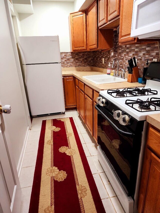 kitchen with decorative backsplash, light tile patterned flooring, white appliances, and sink