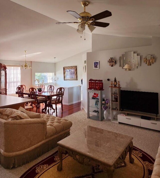 living room featuring ceiling fan with notable chandelier, wood-type flooring, and vaulted ceiling