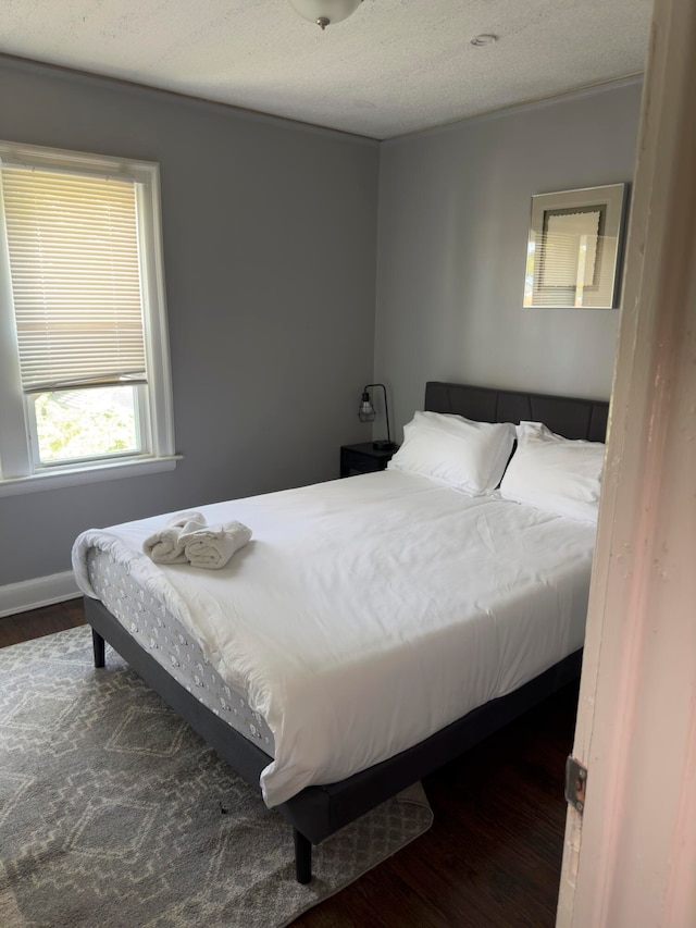 bedroom with a textured ceiling and dark wood-type flooring