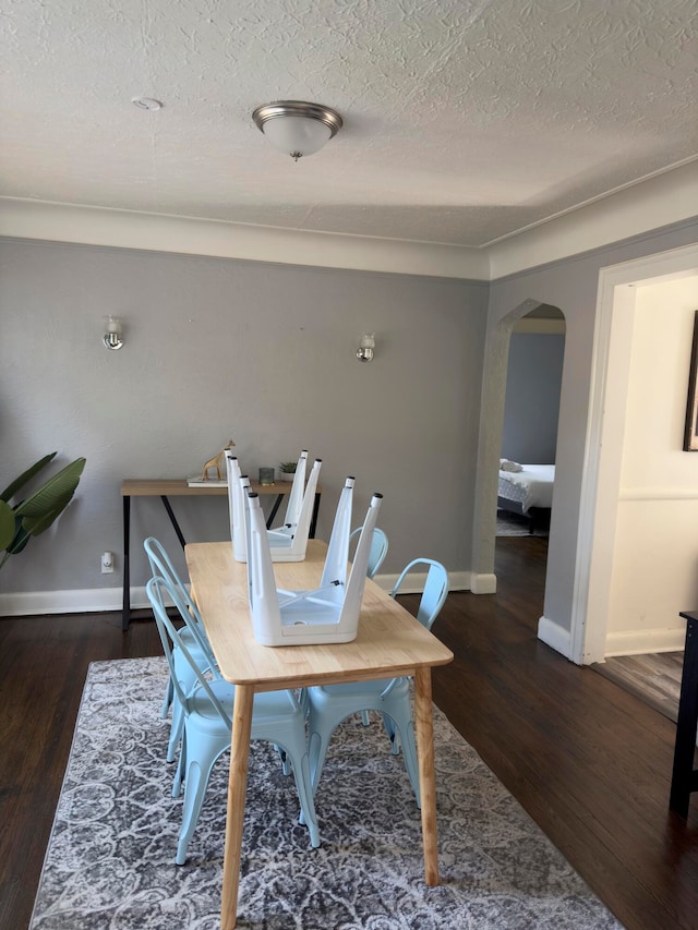 dining area featuring a textured ceiling and dark hardwood / wood-style floors