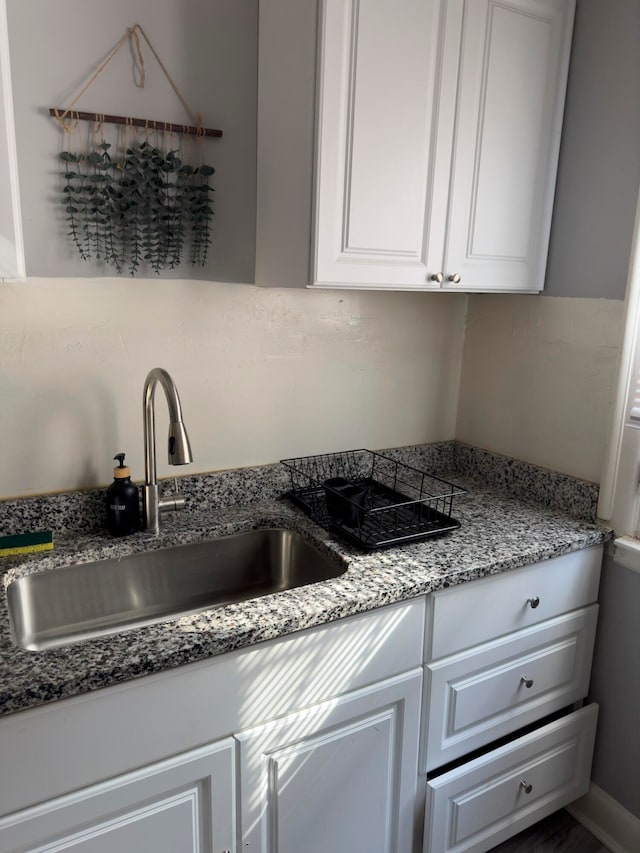 kitchen featuring stone counters, white cabinetry, and sink