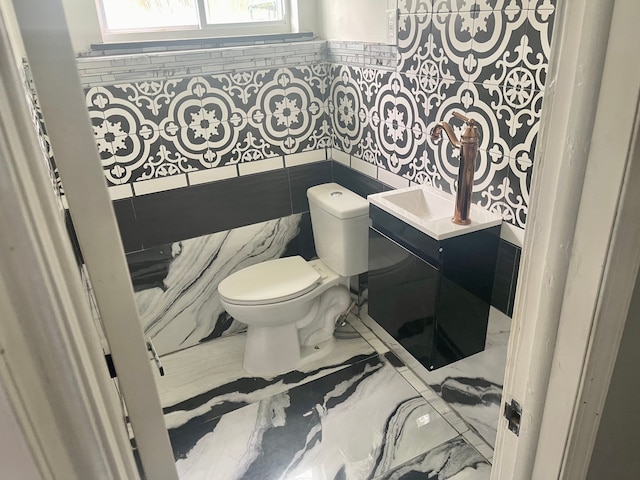 bathroom with vanity, toilet, and tile walls