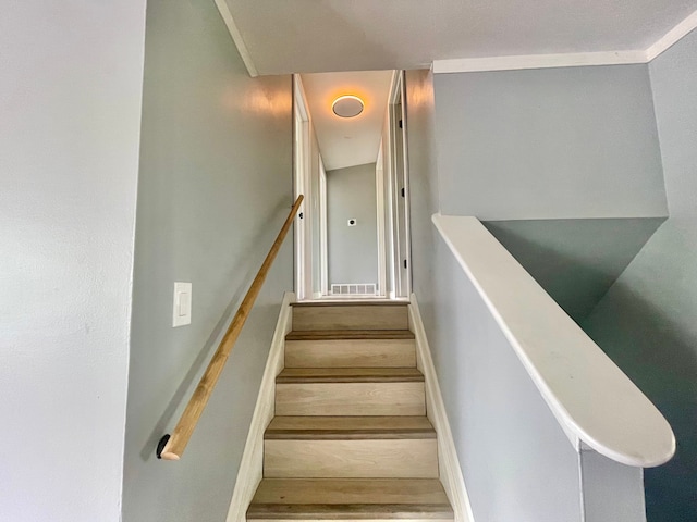 staircase with ornamental molding and hardwood / wood-style flooring