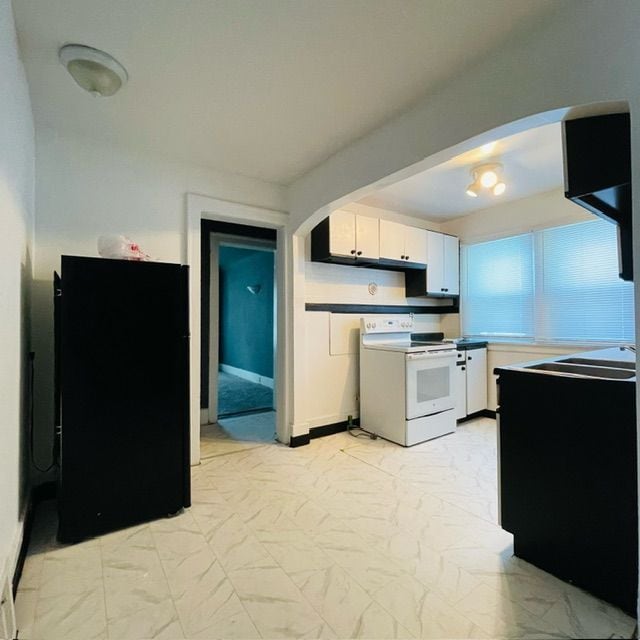 kitchen with white cabinetry, black refrigerator, and electric stove