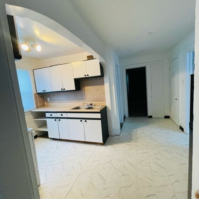 kitchen with decorative backsplash, sink, and white cabinets