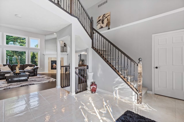 entryway featuring tile patterned floors, a towering ceiling, and a tile fireplace