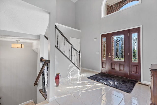 tiled foyer entrance featuring a textured ceiling and a towering ceiling