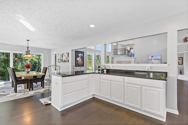 kitchen featuring a textured ceiling, dark hardwood / wood-style floors, white cabinetry, and plenty of natural light