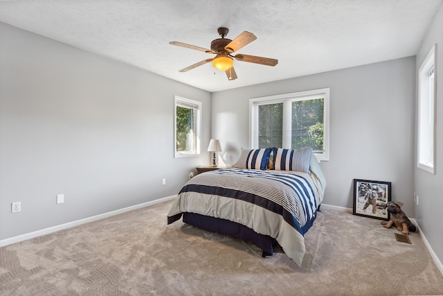 carpeted bedroom with ceiling fan and a textured ceiling