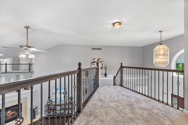 hallway with carpet flooring, vaulted ceiling, and a notable chandelier