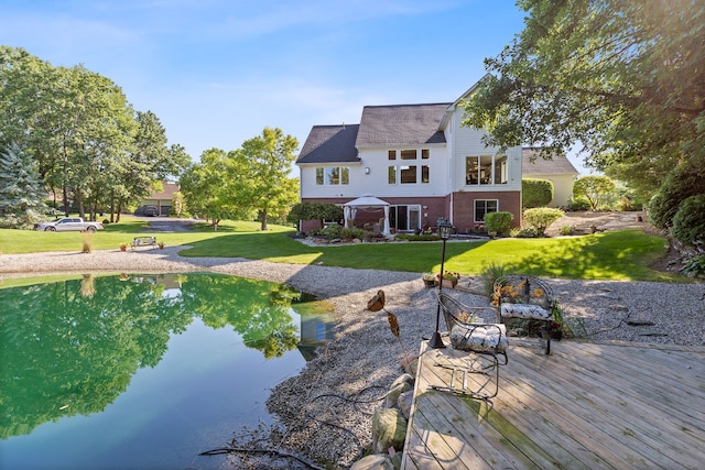 back of house with a deck with water view and a yard