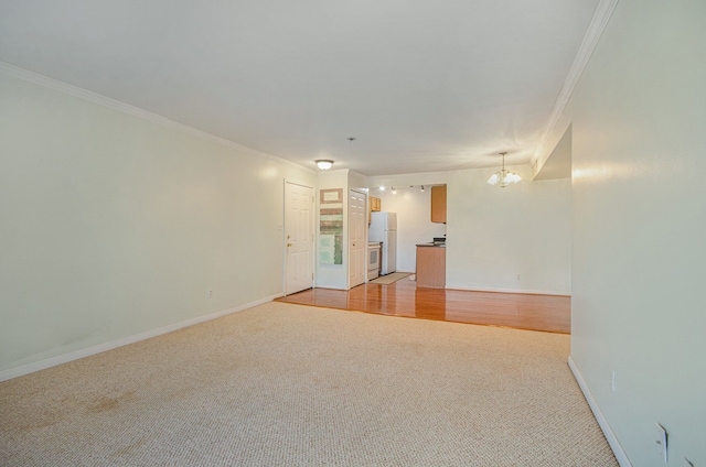 empty room featuring an inviting chandelier, ornamental molding, and light hardwood / wood-style flooring