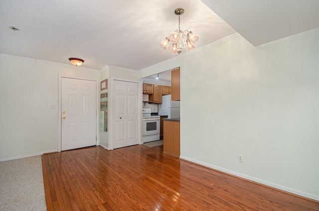 unfurnished living room with crown molding, hardwood / wood-style floors, and a notable chandelier