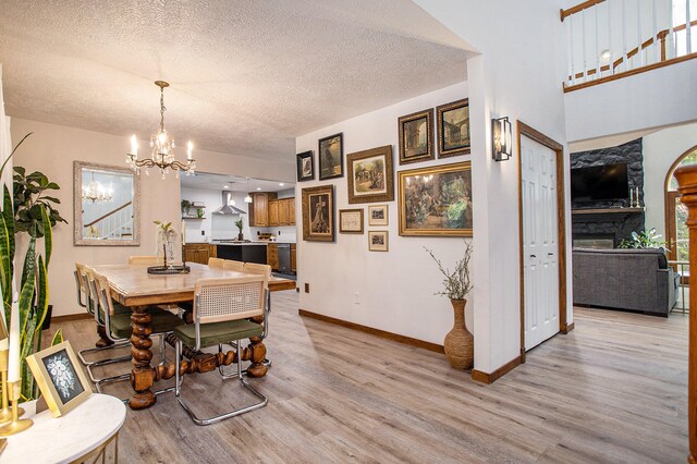 dining area featuring a chandelier, a textured ceiling, light hardwood / wood-style floors, and a fireplace