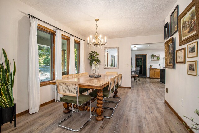 dining space featuring wood-type flooring, a textured ceiling, and an inviting chandelier