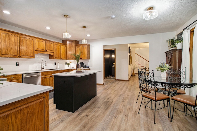 kitchen featuring sink, light hardwood / wood-style flooring, dishwasher, a center island, and hanging light fixtures