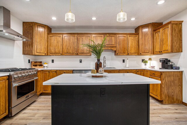 kitchen featuring a center island, light wood-type flooring, wall chimney range hood, and stainless steel appliances