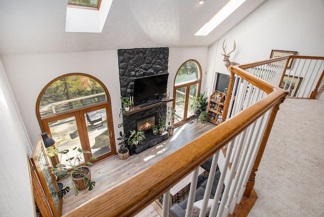 living room featuring a fireplace, french doors, a textured ceiling, and vaulted ceiling with skylight