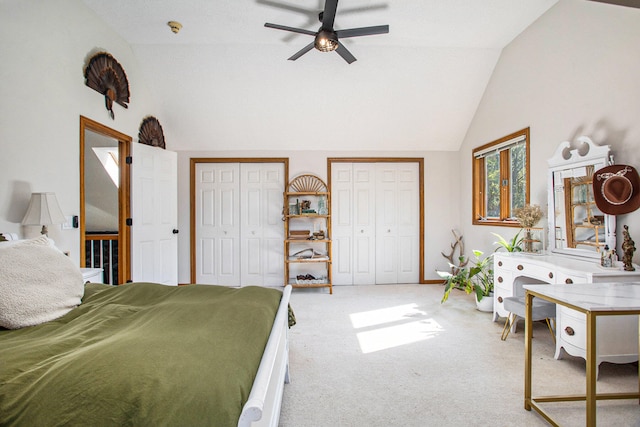 bedroom featuring ceiling fan, vaulted ceiling, light carpet, and two closets