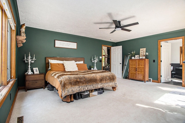 carpeted bedroom featuring a textured ceiling, ensuite bathroom, ceiling fan, and ornamental molding