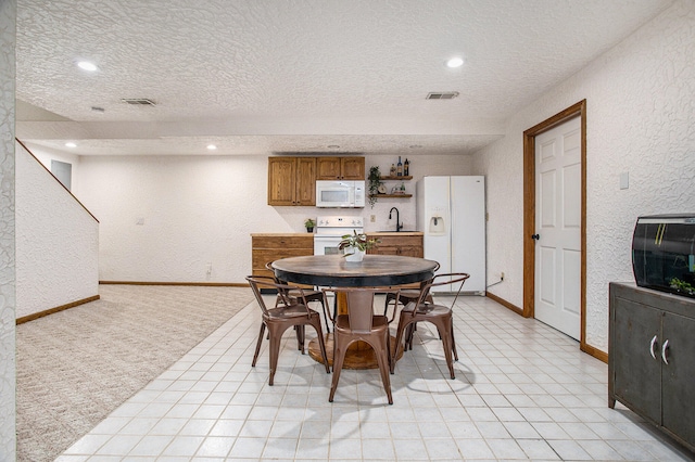 dining area with a textured ceiling, light colored carpet, and sink