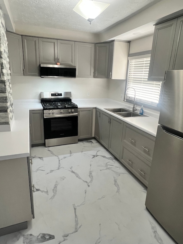 kitchen with gray cabinets, sink, stainless steel appliances, and a textured ceiling