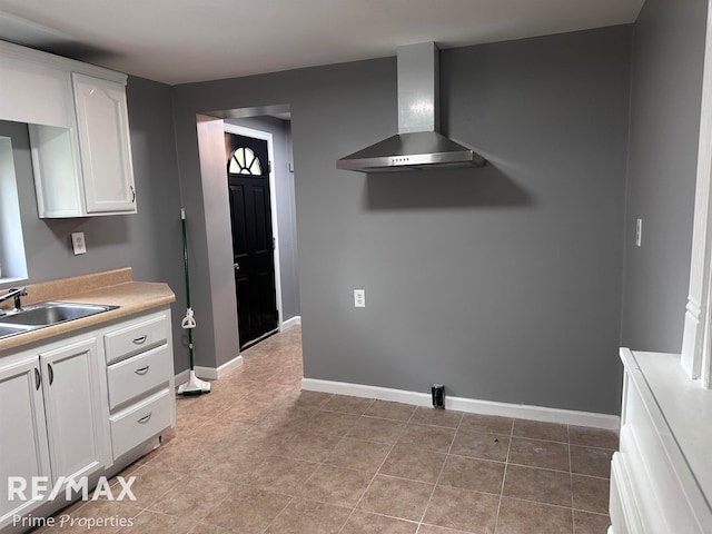 kitchen featuring white cabinets, light tile patterned flooring, wall chimney exhaust hood, and sink