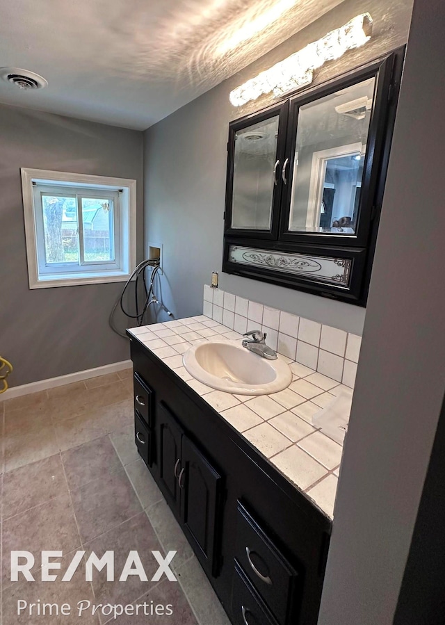 bathroom featuring tile patterned floors, vanity, and tasteful backsplash