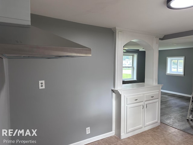 interior space with white cabinetry, plenty of natural light, light tile patterned floors, and range hood