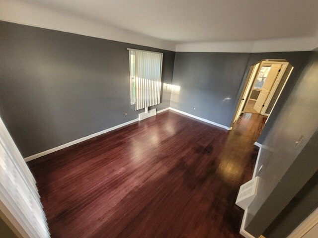15836 Patton St, Detroit, MI 48223 - unfurnished room with arched walkways, dark wood-type flooring, and baseboards