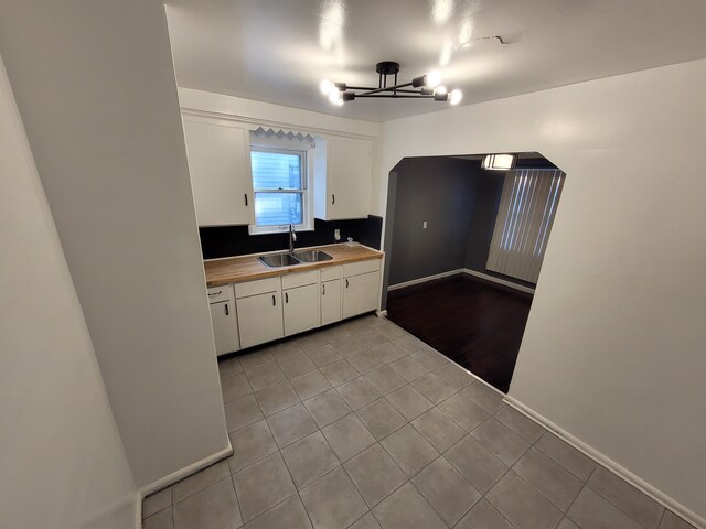 15836 Patton St, Detroit, MI 48223 - kitchen with a sink, white cabinetry, light tile patterned flooring, light countertops, and baseboards