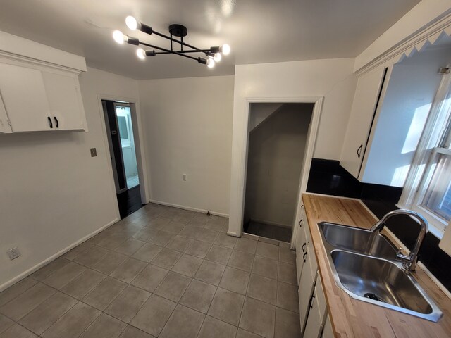 15836 Patton St, Detroit, MI 48223 - kitchen featuring a sink, white cabinetry, butcher block counters, tile patterned flooring, and a chandelier