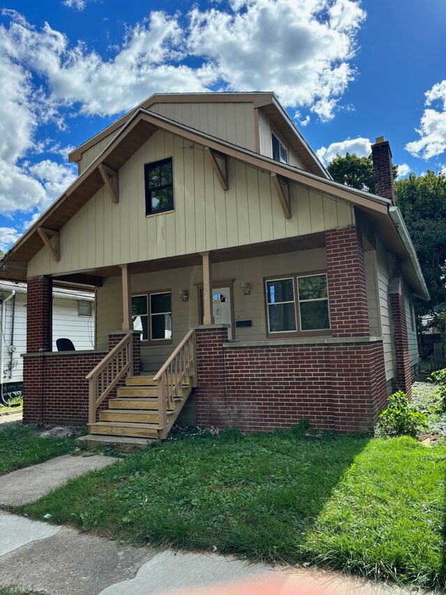 bungalow-style house featuring covered porch and a front yard