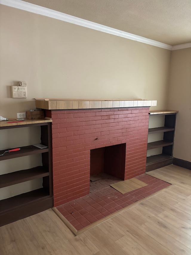 interior details with a textured ceiling, crown molding, a fireplace, and hardwood / wood-style flooring