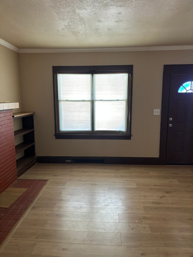 foyer featuring a textured ceiling, crown molding, and light hardwood / wood-style floors