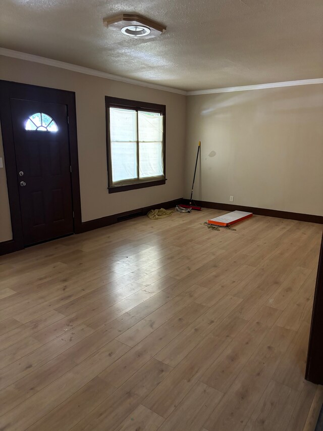 entrance foyer featuring a healthy amount of sunlight, crown molding, a textured ceiling, and light hardwood / wood-style floors