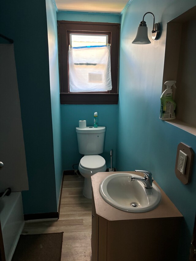 bathroom featuring toilet, a tub to relax in, wood-type flooring, and vanity