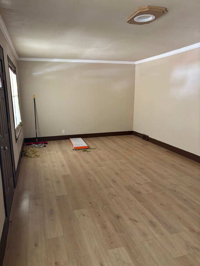 spare room featuring light wood-type flooring and crown molding