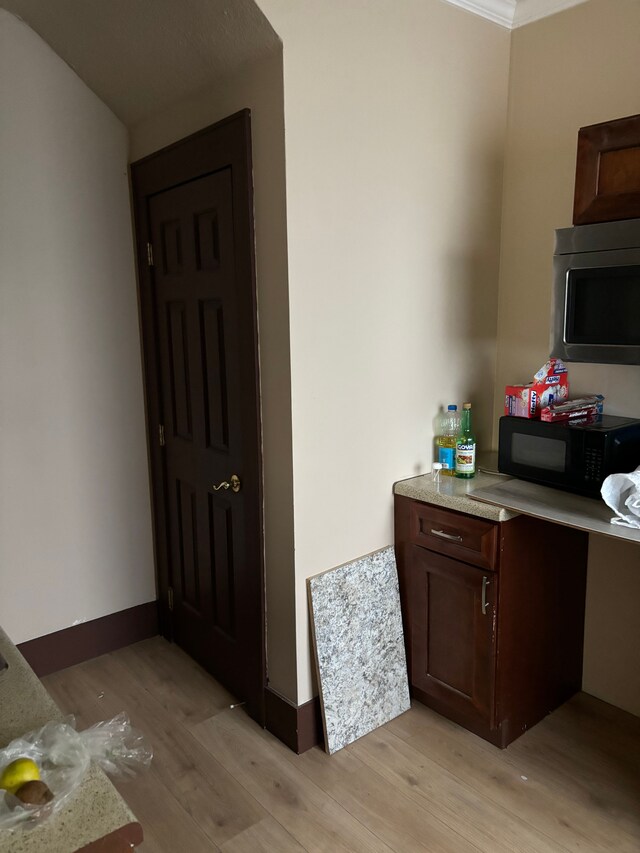 kitchen featuring light hardwood / wood-style floors, dark brown cabinetry, and ornamental molding