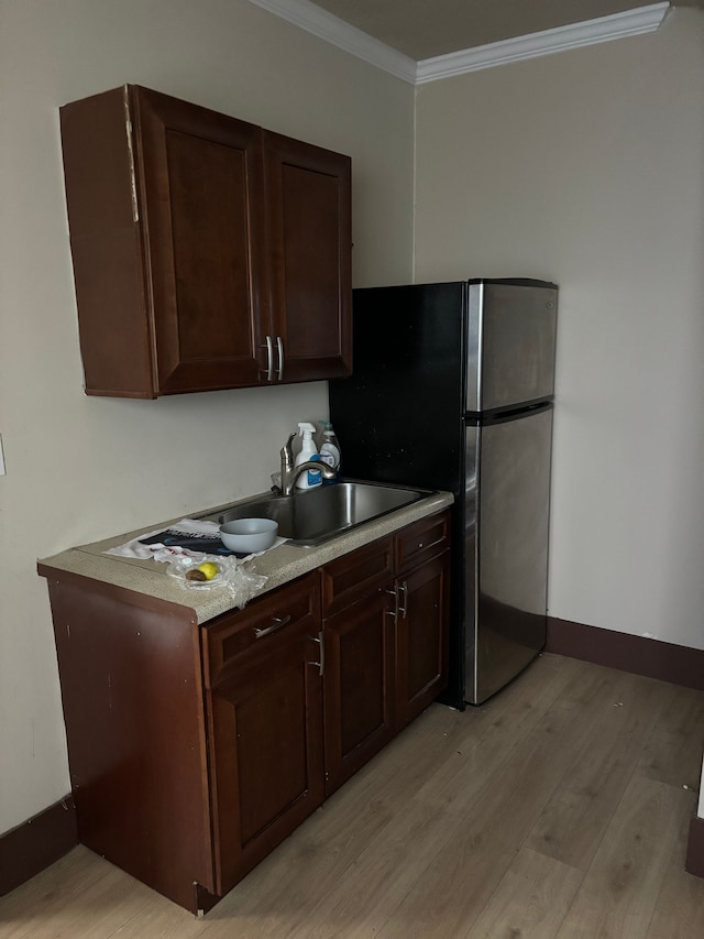 kitchen with dark brown cabinetry, baseboards, light countertops, crown molding, and light wood-type flooring