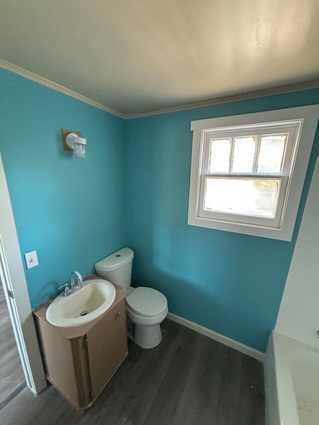 bathroom featuring toilet, wood-type flooring, a tub, ornamental molding, and sink