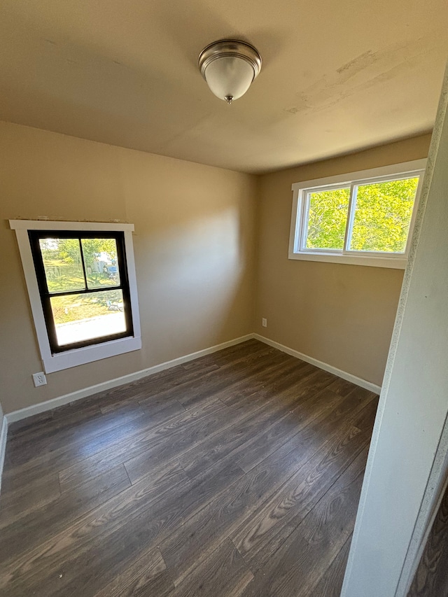 empty room with baseboards and dark wood-type flooring