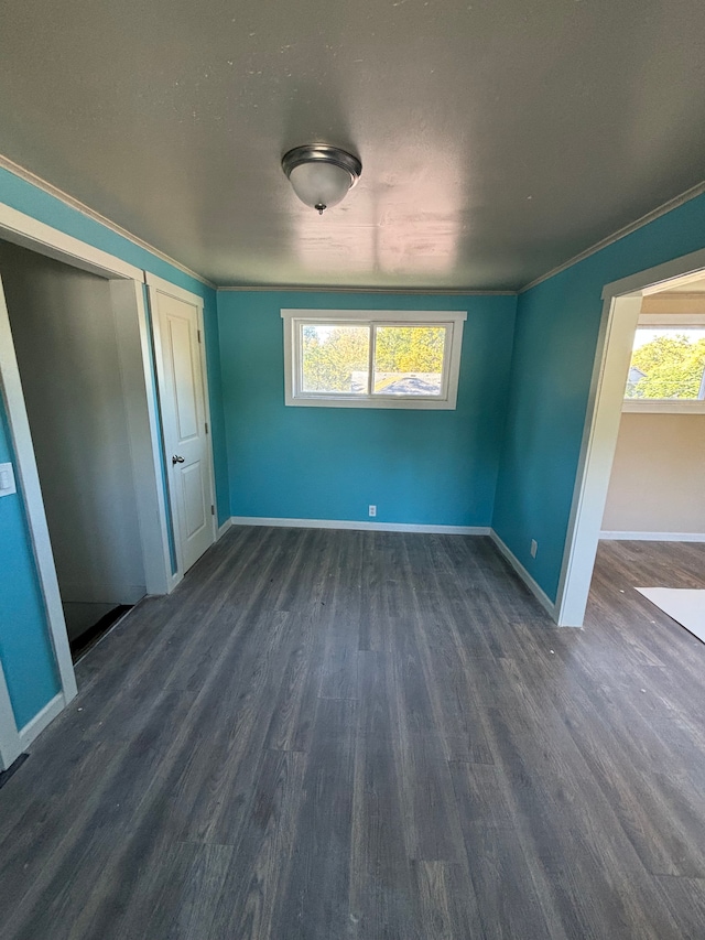 unfurnished bedroom featuring ornamental molding, dark wood-style flooring, and baseboards