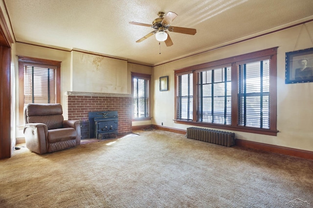 unfurnished room with ornamental molding, a textured ceiling, ceiling fan, radiator heating unit, and a wood stove