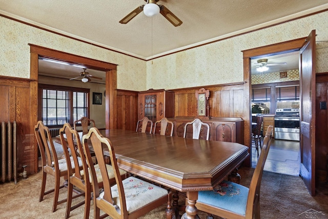 dining area with carpet flooring, wooden walls, radiator heating unit, and a textured ceiling