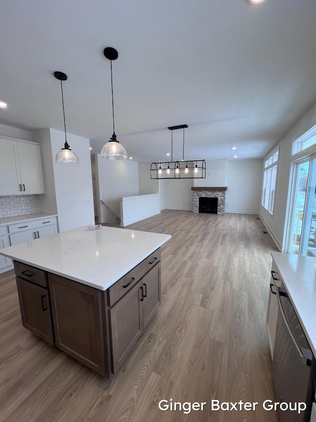 kitchen with dishwasher, white cabinets, decorative backsplash, hanging light fixtures, and light hardwood / wood-style floors