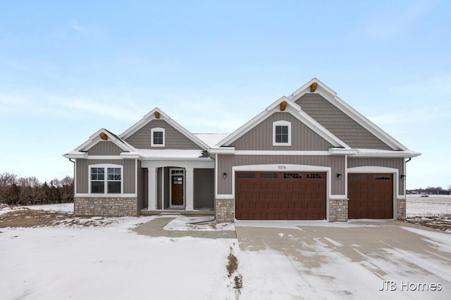 craftsman inspired home featuring a garage, stone siding, board and batten siding, and driveway