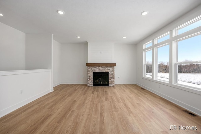 unfurnished living room with recessed lighting, a fireplace, visible vents, baseboards, and light wood-type flooring