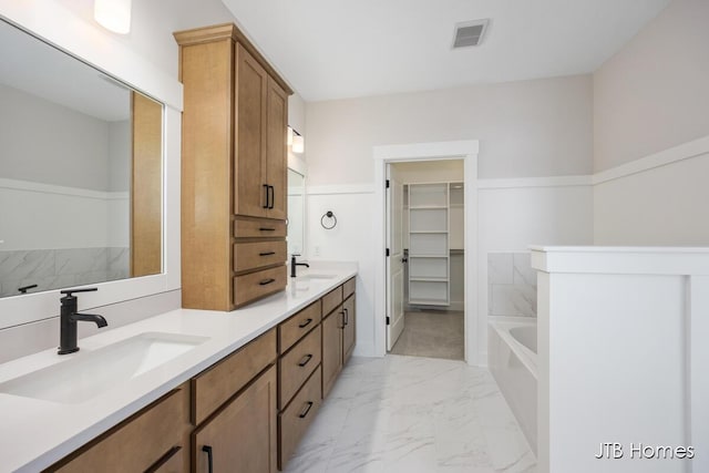 bathroom featuring a sink, marble finish floor, a walk in closet, and visible vents