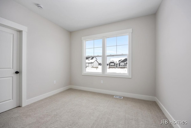 empty room with carpet floors, baseboards, and visible vents